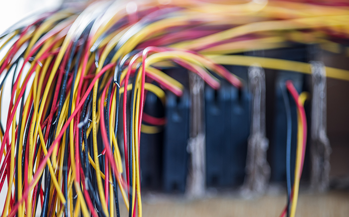 Bundle of cut thin wires with color connections Close-up of a bundle of cut thin wires with color connections sticking out of them against a blurred electronic panel. The concept of electrical appliances in production and factory