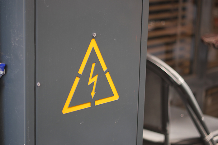 Warning sign on electrical cabinet in industrial location Bright yellow warning sign indicating high voltage near machinery.